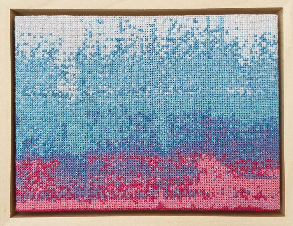 A visual representation of sound in cross stitch. The central areas are mainly shades blue. At the bottom there is a scattering of pink and purple.