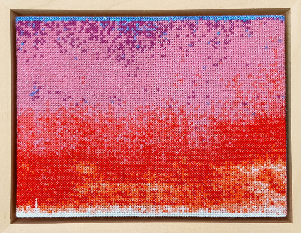 A visual representation of sound in cross stitch. The central areas are mainly shades of red, peach and pink. At the top there is a scattering of blue and purple.